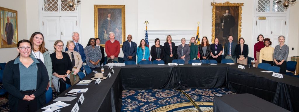 A picture of several people standing behind tables, smiling for a picture. 